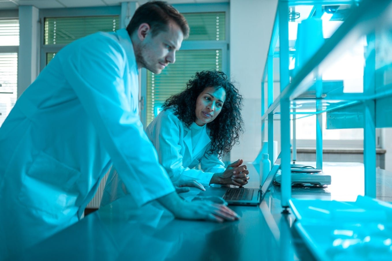 Scientists looking at a laptop in a blue-lit laboratory