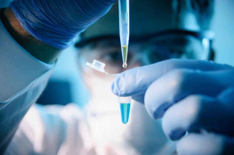 Scientist dispensing liquid into a vial with a pipette