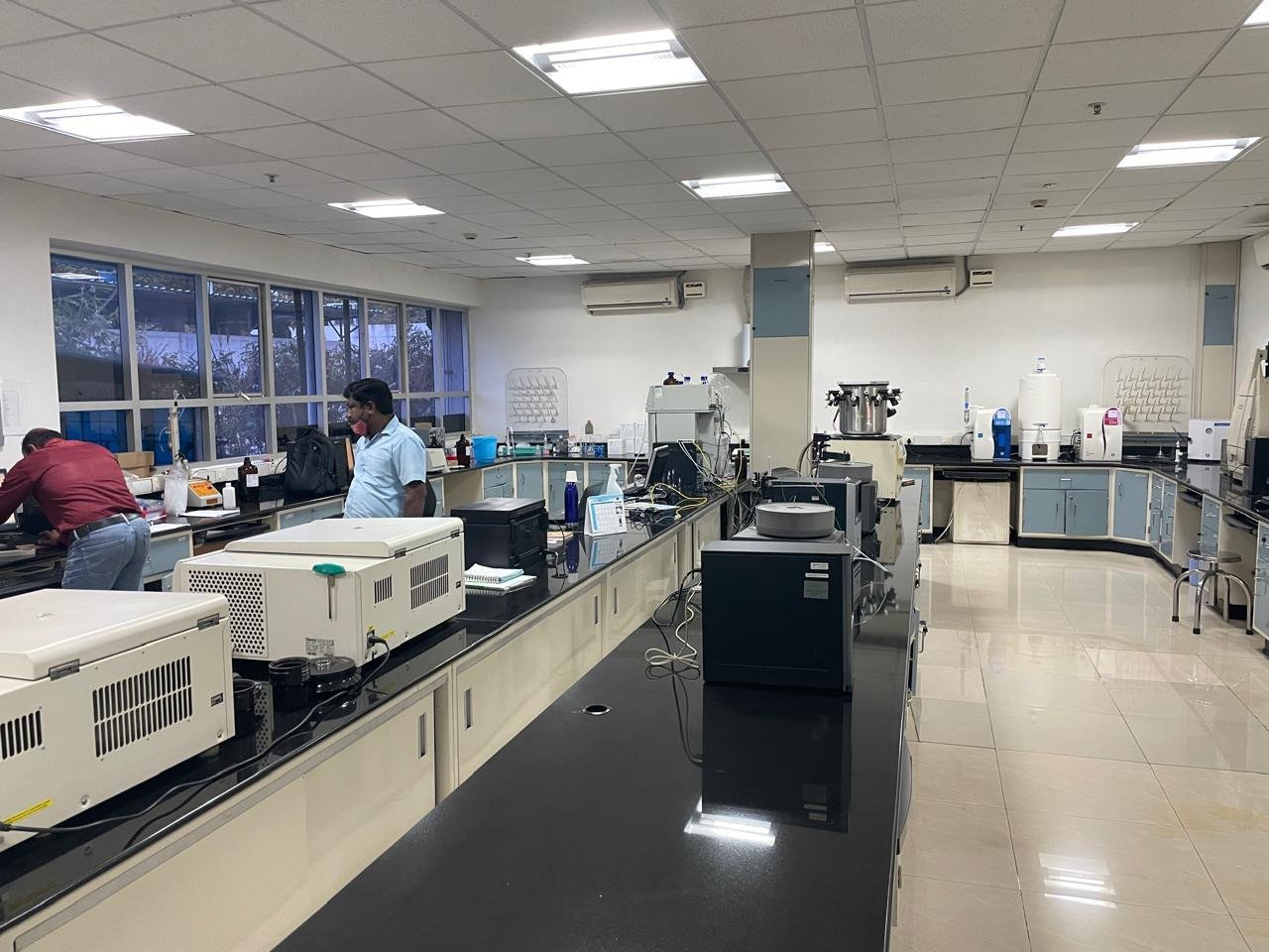 Wide shot of a bright, modern analytical laboratory room with dark countertops and various analytical machines