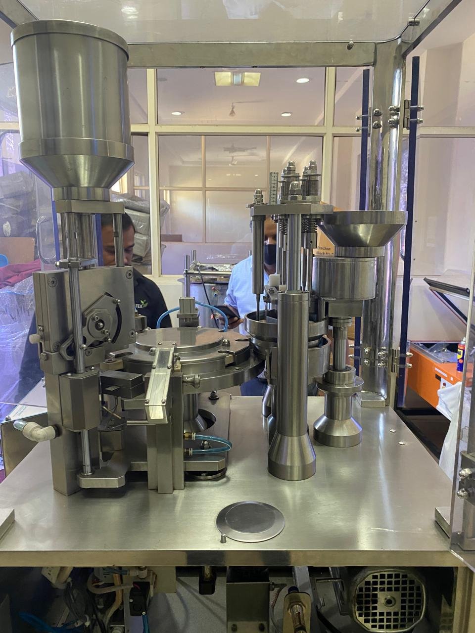Close-up of a stainless steel automated capsule filling or tablet press machine in operation