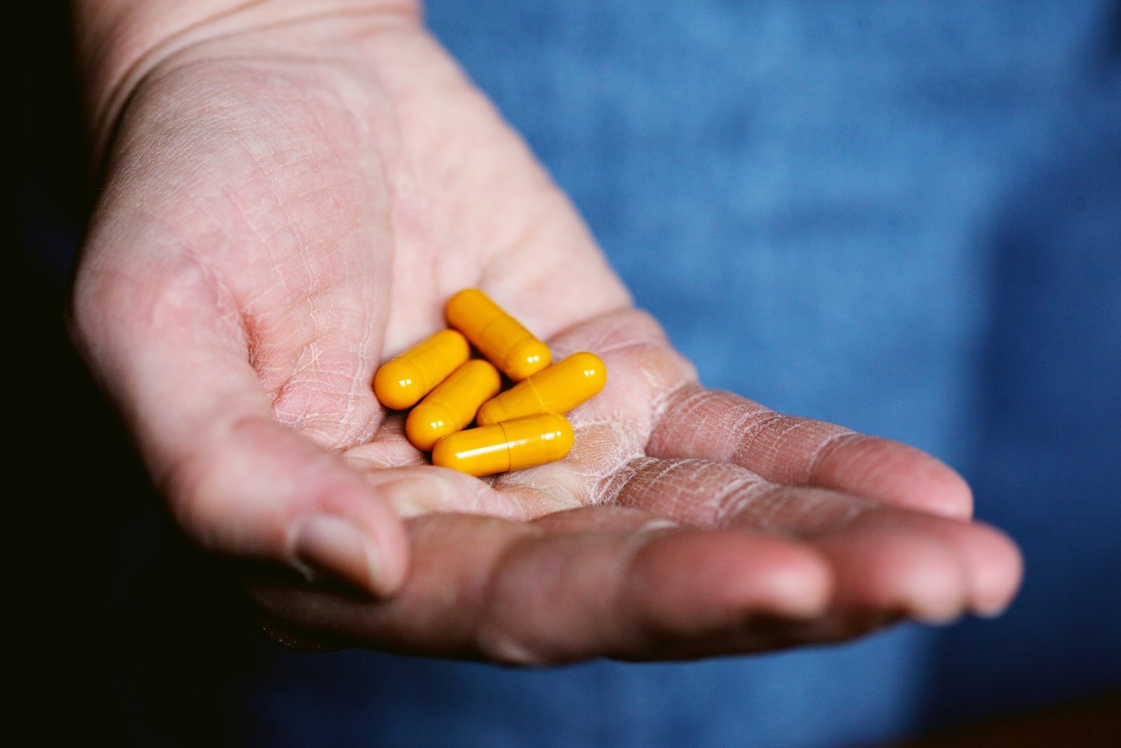Hand holding several yellow capsules